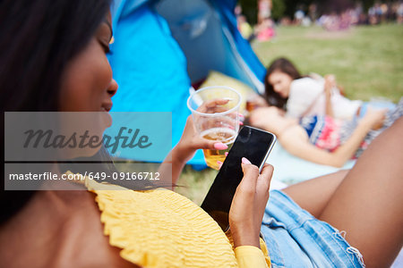 Woman using cellphone at music festival, friends in background