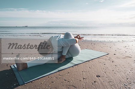 Woman practising yoga on beach