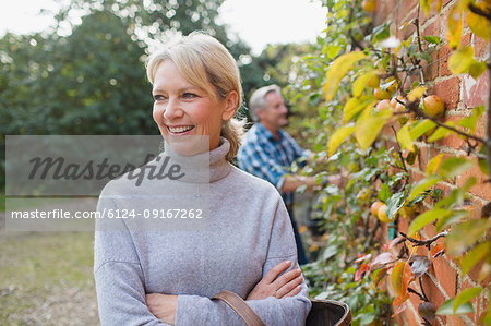 Portrait happy, confident mature woman harvesting apples in garden
