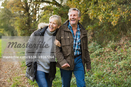 Happy, carefree mature couple walking arm in arm in autumn park