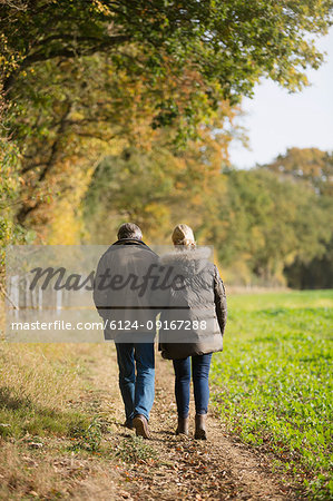 Affectionate mature couple walking in sunny, rural autumn field