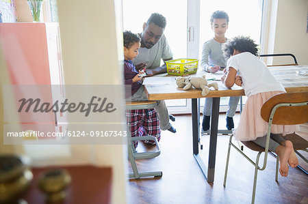 Father and children coloring at dining table