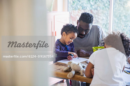 Father and toddler son coloring at table