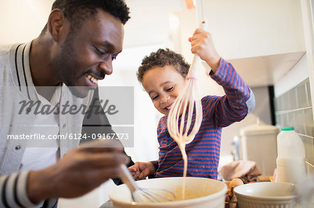 Father and toddler son baking in kitchen