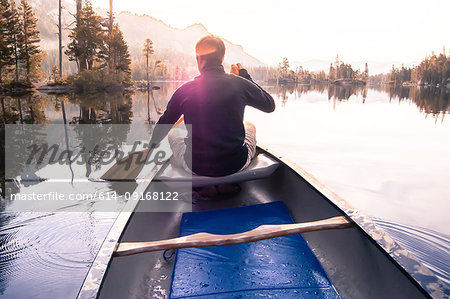 Young man canoeing on Echo Lake, rear view, High Sierras, California, USA