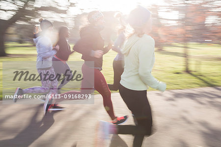 Female runners running in sunny park