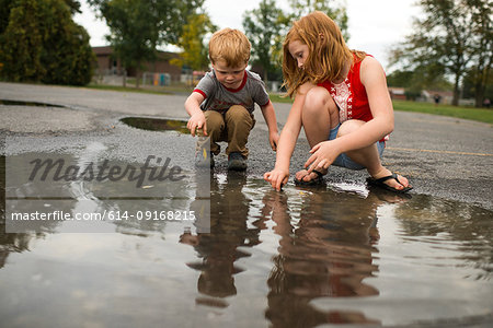 Children playing in puddle on road