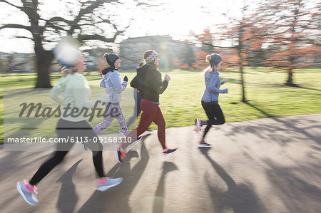 Female runners running in sunny park