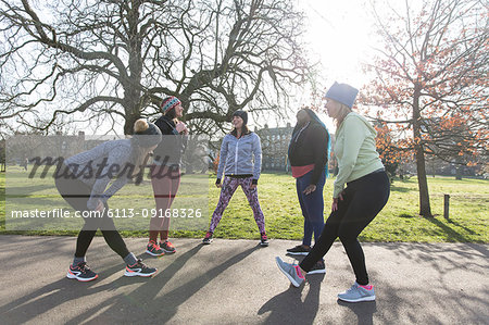 Female runners stretching and talking in sunny park