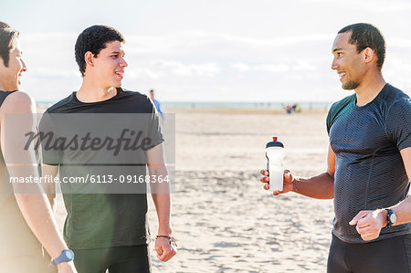 Male runners resting on sunny beach