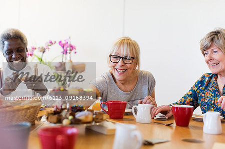 Senior friends enjoying afternoon tea and dessert in community center