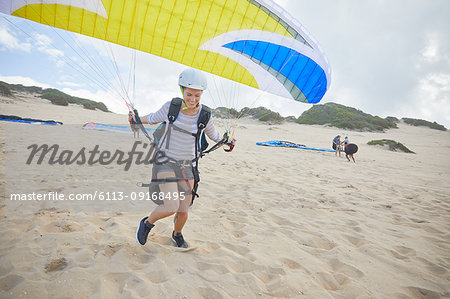 Female paraglider with parachute running, taking off on beach