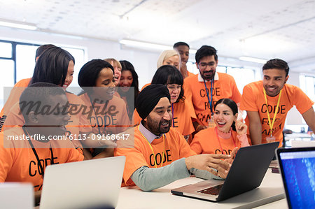 Happy hackers at laptop coding for charity at hackathon