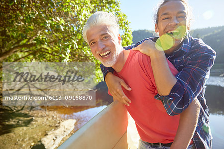 Portrait playful father and son at sunny summer lake