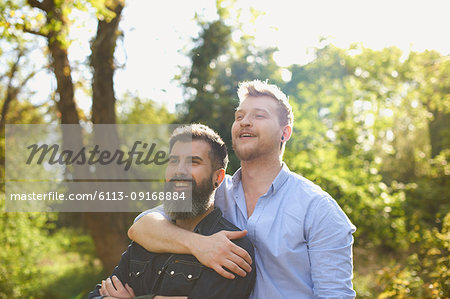 Affectionate male gay couple hugging in sunny park