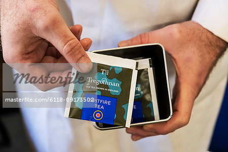 High angle close up of person holding a tin with tea bags.