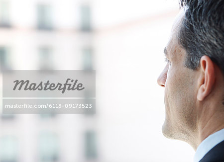 Closeup of a Caucasian businessman looking out the widow of a conference centre lobby.