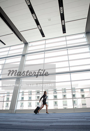 Businesswoman running through a conference centre lobby.