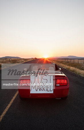 A senior couple "just married" riding in a convertible sports car in eastern Washington State, USA.