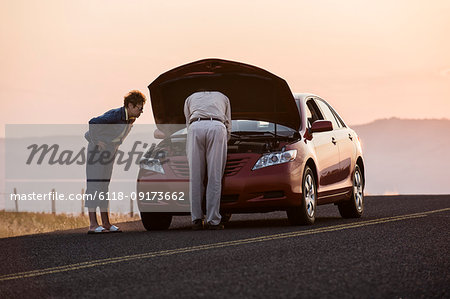 Senior couple with car engine problems while on a road trip.