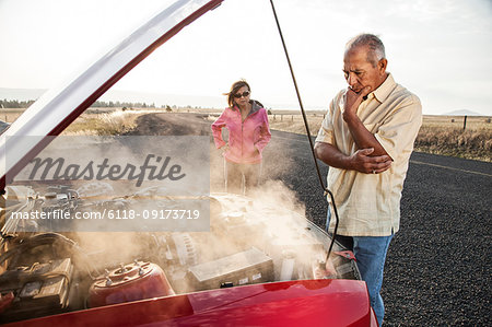 An Hispanic senior couple pulled over at the side of the road with engine trouble.