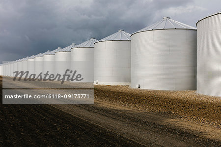 Rows of grain silos, stormy skies in distance, Saskatchewan, Canada.