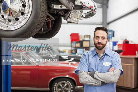 A portrait of a Caucasian mechanic in his classic car repair shop.