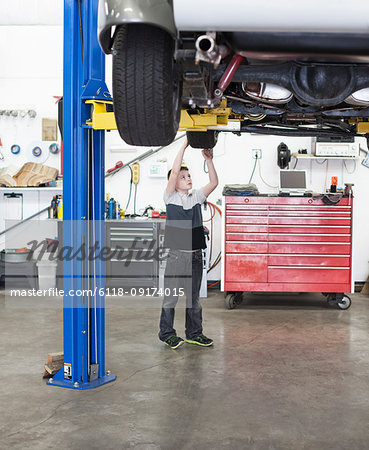 A young boy looks at a car tire in his dad's classic car repair shop.