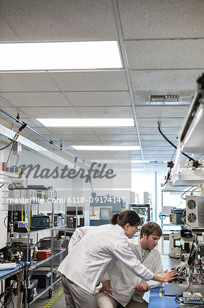 A team of two male and female technicians working over a problem in a technical research and development site.