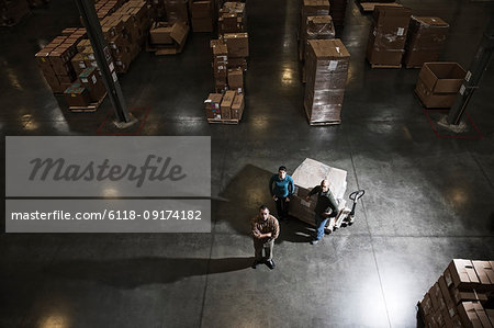 A group of three warehouse workers standing in the centre of a distribution warehouse.