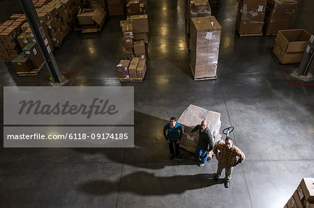 A group of three warehouse workers standing in the centre of a distribution warehouse.