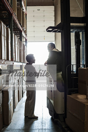 Two warehouse employees talking over an issue while working in a distribution warehouse.