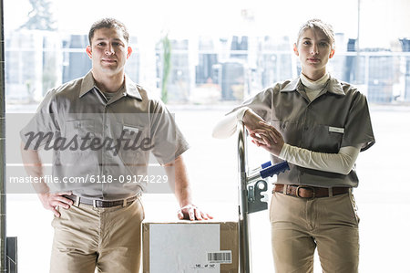 A team portrait of two Caucasian female and Hispanic male uniformed warehouse workers .