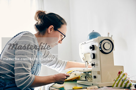 Woman using electric sewing machine to make curtains