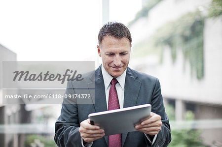 A Caucasian businessman checking his notebook computer while standing in a convention cener lobby.