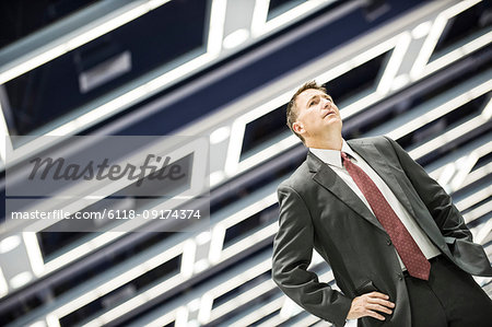 A view looking up at a Caucasian businessman walking through a convention centre arena.