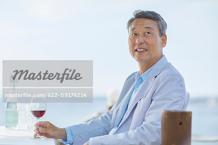 Japanese senior couple having a drink by the sea