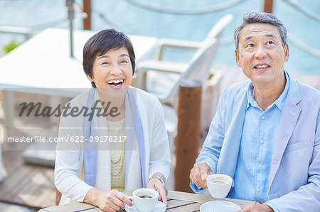 Japanese senior couple having a drink by the sea
