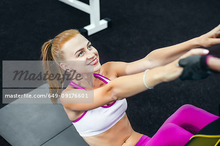 Woman doing sit ups in gym and smiling