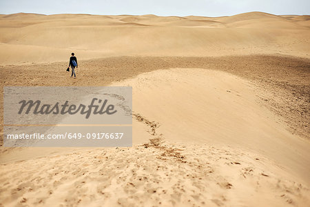 Mature female tourist walking barefoot on sand dune, rear view, Las Palmas, Gran Canaria, Canary Islands, Spain