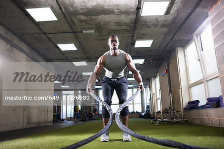 Man using battle ropes in gym