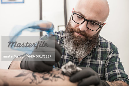 Tattooist drawing on arm of client