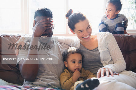 Laughing, happy multi-ethnic family on living room sofa