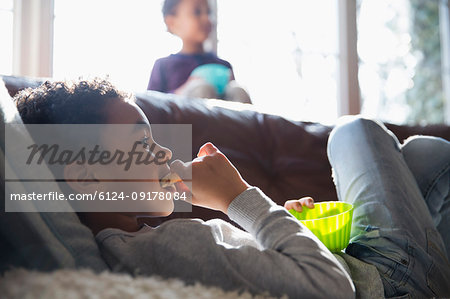 Boy eating snack and watching TV on sofa