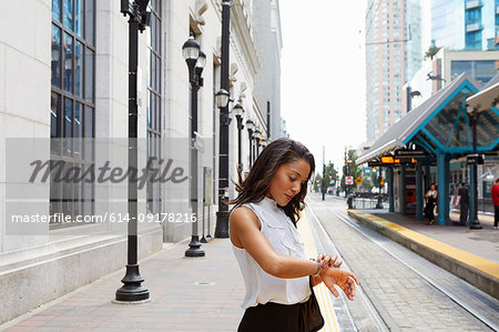 Businesswoman checking time by light rail line