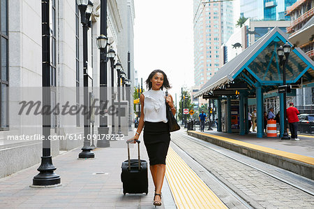 Businesswoman pulling luggage alongside train