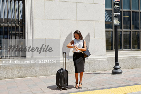 Businesswoman checking time on kerb