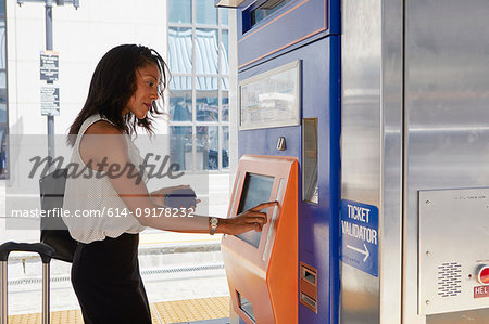 Businesswoman buying train ticket at machine