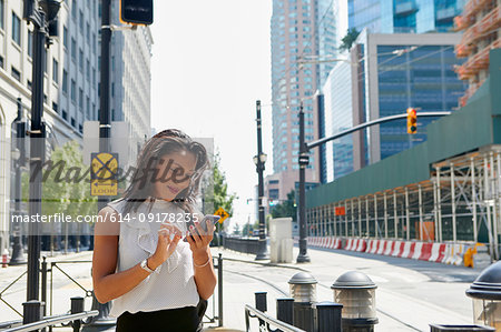 Businesswoman using cellphone by barriers