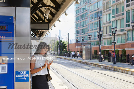 Businesswoman using cellphone by ticket machine